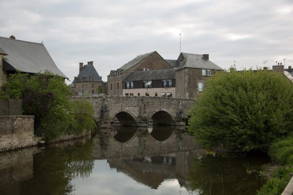 Le vieux pont de 1613 sur la Sélune, à Ducey, avec le château en arrière-plan